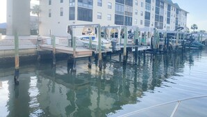 A waterfront property with a multi-story building, docked boats, and a calm water body. - Remodeled Condo, Steps to the Beach (Naples)