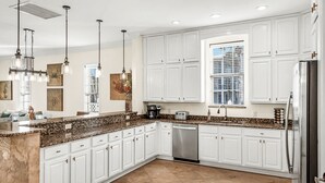 A modern kitchen with white cabinets, granite countertops, stainless steel appliances, and pendant lighting. - 9 Bedrooms / 6.5 Baths / Sleeps 28 / 8 Parking Spots / Pool / Steps to Beach!!! (Destin)