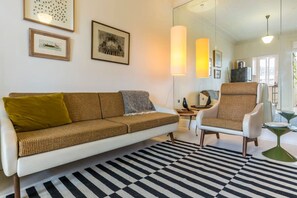 A modern living room with a sofa, armchair, and a patterned rug.