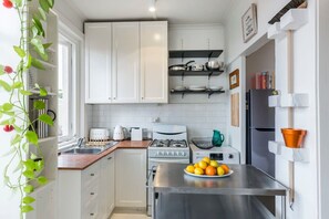 A modern kitchen with white cabinets, stainless steel appliances, and a fruit bowl on the counter. - Top Floor Darlinghurst/Sydney Views Walk To CBD (Darlinghurst)