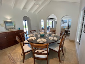 Un coin repas avec une table ronde dressée pour six personnes, entourée de chaises en bois dotées d’assises rembourrées.