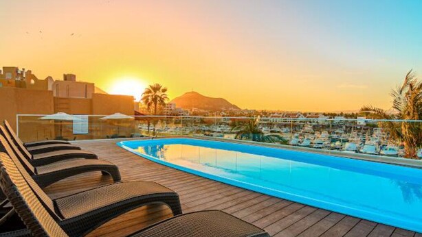 Zona de piscina amb gandules, vista clara del capvespre i una muntanya allunyada.