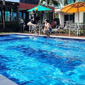 Alberca al aire libre, sombrillas en la alberca y camastros