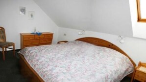 A bedroom with a wooden bed, a wooden dresser, a chair, and a small table. - Haus Sleeboom - mit 53 qm in Ruhiger Lage Gelegen (Borkum)