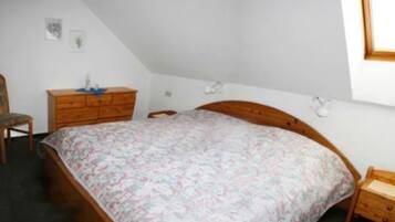 Ein Schlafzimmer mit einem hölzernen Bett, einer Holzkommode, einem Sessel und einem kleinen Tisch.