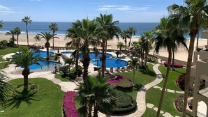 Ein Resort mit mehreren Schwimmbecken, Palmen und Blick auf den Strand.
