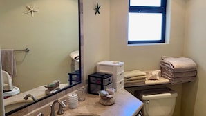 Une salle de bain avec un grand miroir, un lavabo, des toilettes et une fenêtre.