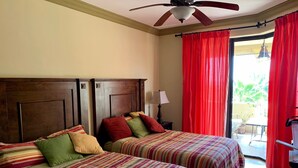 Une chambre d’hôtel avec deux lits, un ventilateur de plafond et une vue sur l’extérieur grâce à une porte coulissante.