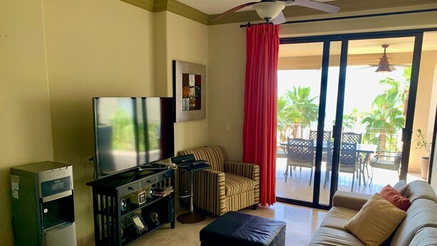 Ein Wohnzimmer mit Flachbildfernseher, Kühlschrank, Sofa und einem Essbereich mit Stühlen und Tisch.