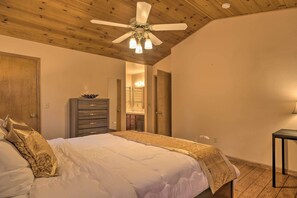 Une chambre à coucher avec un lit, un ventilateur de plafond, une commode et une table de chevet.