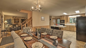 A spacious living area with a dining table set for six, a fireplace, and a kitchen with wooden cabinets and a large refrigerator. - Spacious cabin with AC, private lake, hot tub, movie room (Arnold)