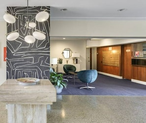 Welcome to our lobby, featuring a reception desk, abstract art, and comfortable seating areas.
