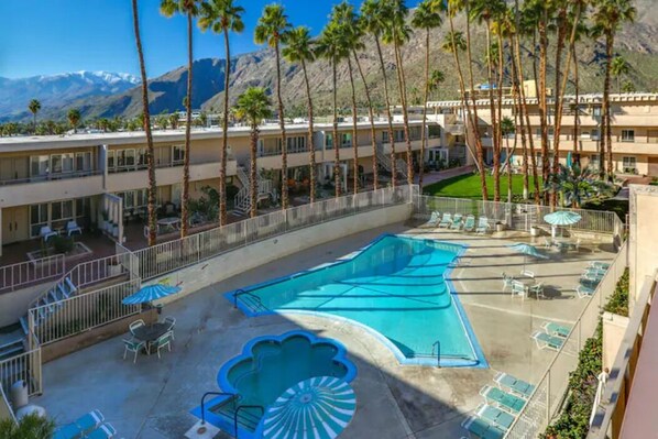 Relax by the pool surrounded by palm trees and lounge under the shade of an umbrella.