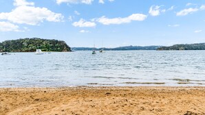 A beach with a sandy shore, calm water, and boats in the distance. - Bayview Corner Suite (Unit 2) - Paihia Unit (Paihia)