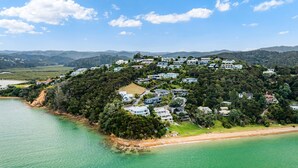 An aerial view of a coastal residential area with houses built on a hillside overlooking a clear blue sea. - Bayview Corner Suite (Unit 2) - Paihia Unit (Paihia)