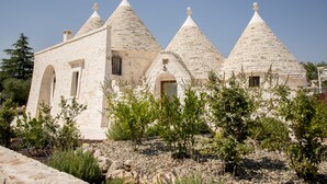 A stone building with conical roofs and arched doorways. - trullo manivida (Puglia)