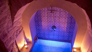 A spa tub with a geometric tile pattern, a showerhead, and candles. - trullo manivida (Puglia)