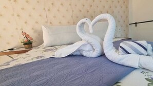 A bed with a floral bedspread and a heart-shaped towel arrangement. - Pousada Camburi (Cairu)