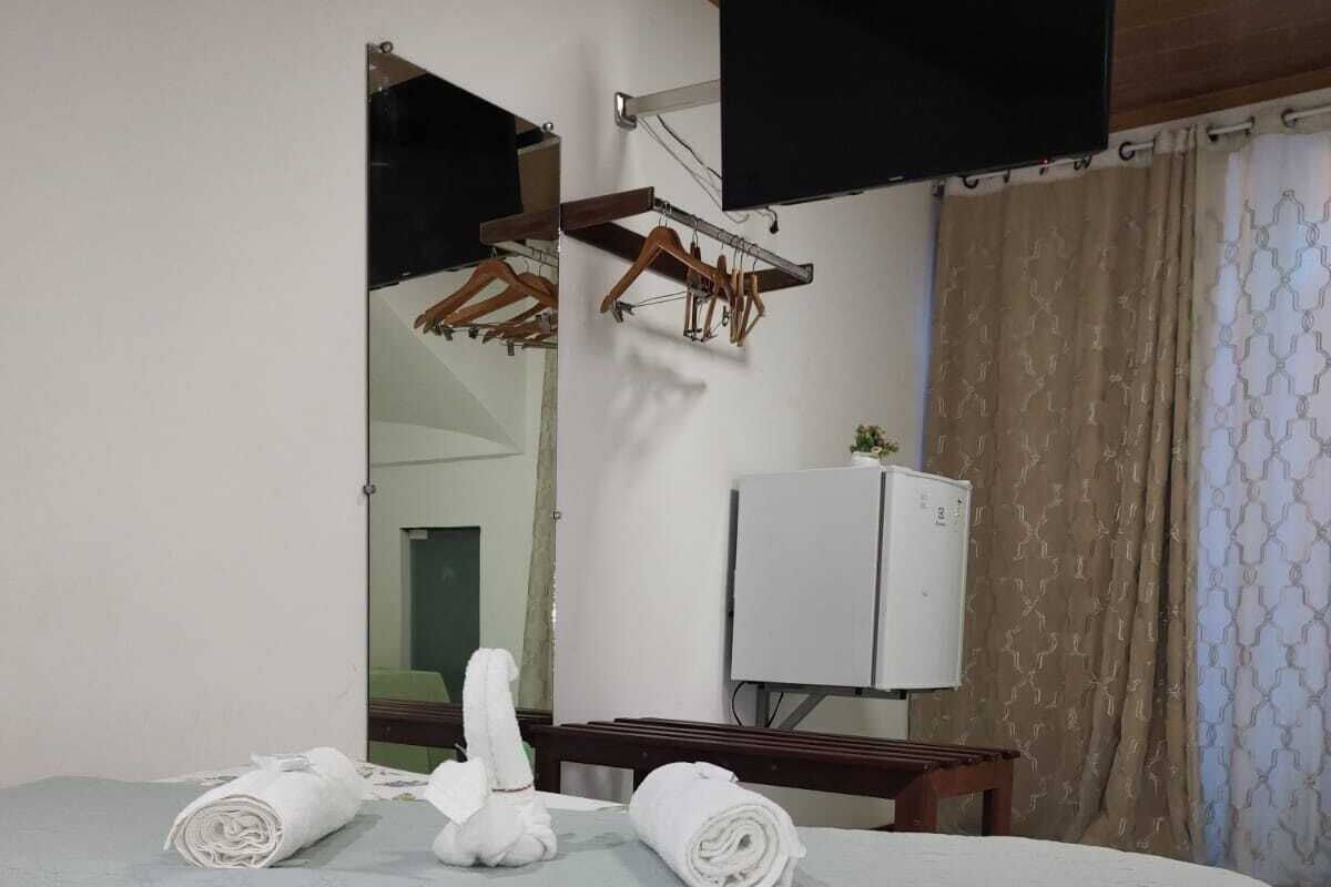 A hotel room with a bed, a mirror, a television, and a wardrobe.