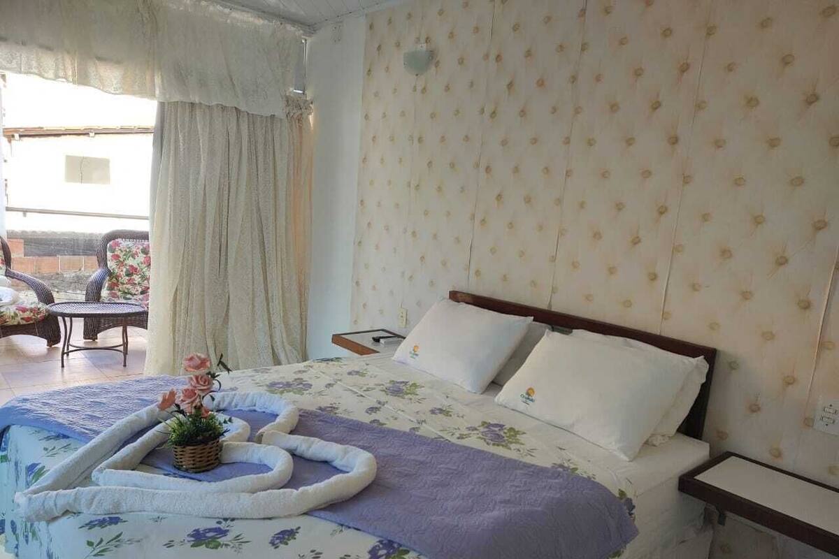 A bedroom with a bed, a bedside table, and a window with curtains.