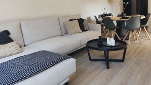 Moderni olohuone, jossa on sohva, sohvapöytä sekä ruokailutila tuoleineen ja pöytineen.