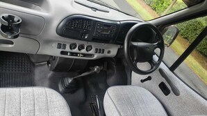 El interior de un coche con dos asientos, un volante, tablero y palanca de cambios.