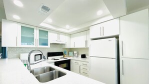 A modern kitchen with white cabinets, stainless steel appliances, and a granite countertop. - 🏖️BEACHSIDE🏖️ 2/2 Condo In The Heartbeat of SPI!! (South Padre Island)