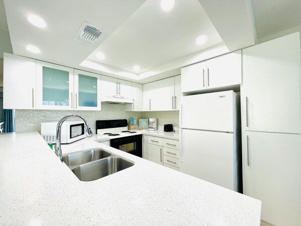 A modern kitchen with white cabinets, stainless steel appliances, and a granite countertop.