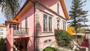 A pink building with a balcony, a small garden, and a staircase leading to the entrance. - Sea's House Moledo (Moledo)