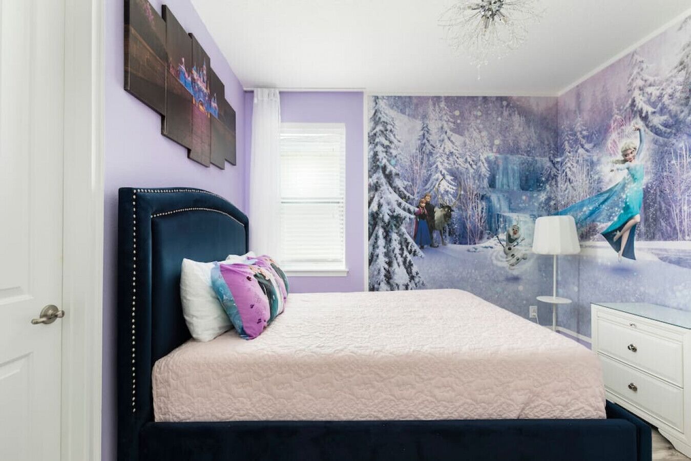 Quarto com cama, mesa de cabeceira, cômoda e um mural na parede.