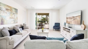 A modern living room with a sofa set, a coffee table, a TV, and a painting on the wall. - Fantabulous Disney Vacation House - Private pool, Movie Theater, Game Room (Kissimmee)