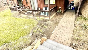 A two-story wooden house with a covered porch and a stone pathway leading to the entrance.
