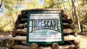 A sign for 'Treescape Aerial Adventure Park' surrounded by logs.