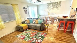 A living room with a sofa, a coffee table, and a dining area with a table and chairs.
