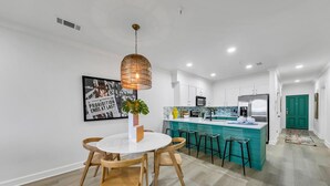 A modern kitchen with white cabinets, a teal island, and a hanging pendant light. - Newly Renovated Professionally Decorated Gulf Views! Pool & Beach Access. (Seacrest Beach)
