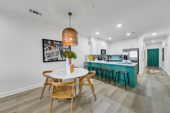 A modern kitchen with white cabinets, a teal island, and a hanging pendant light.