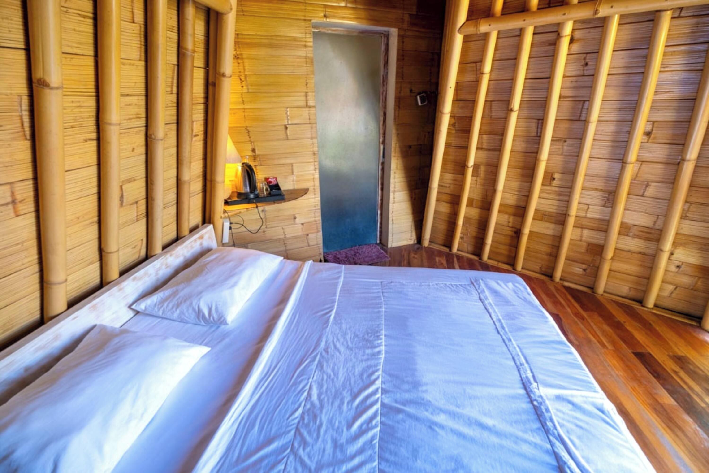 A room with a bed, wooden walls, and a door.