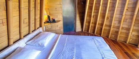 A room with a bed, wooden walls, and a door.