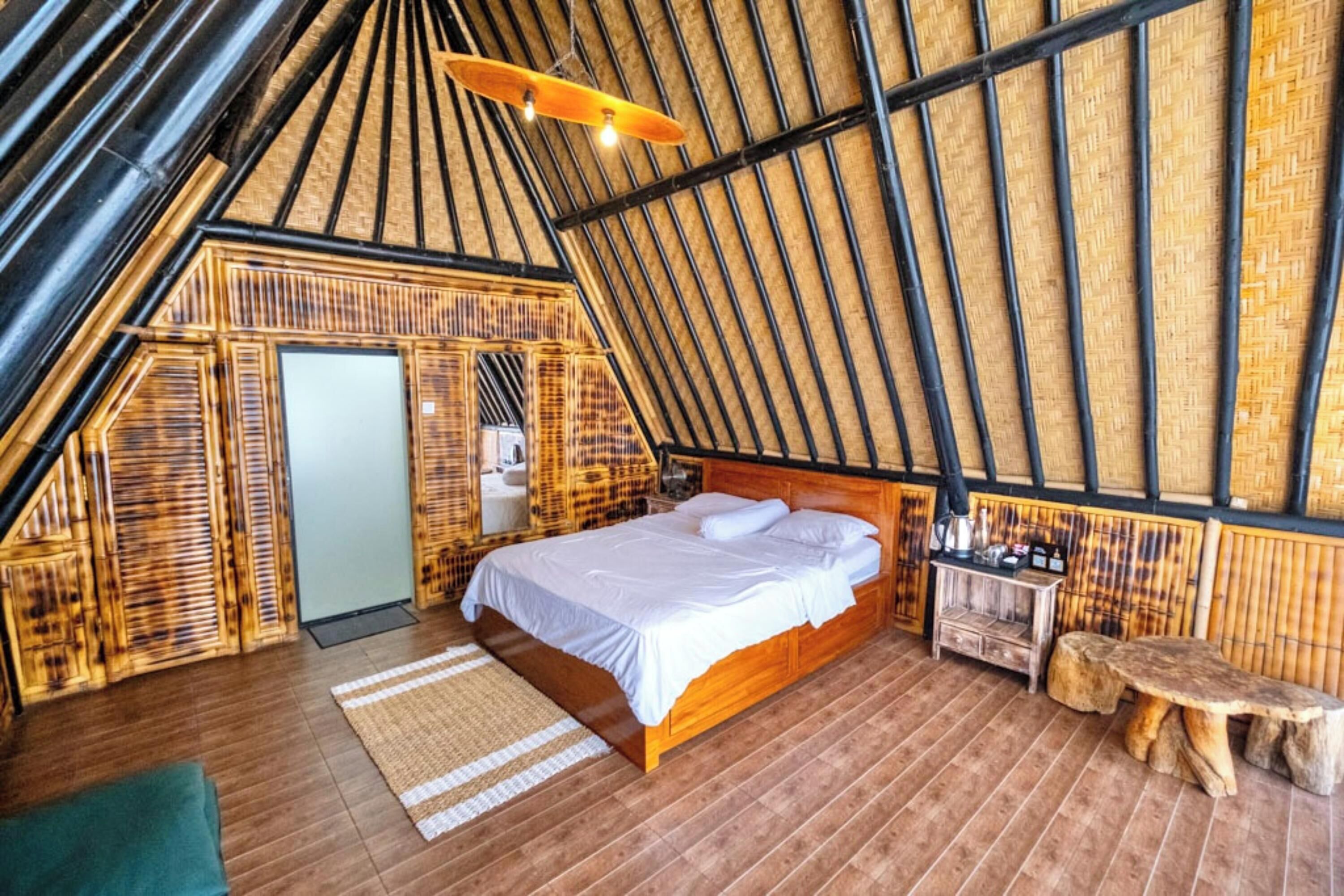 A cozy, rustic bedroom with a wooden bed, a small wooden bench, and a unique sloped ceiling.