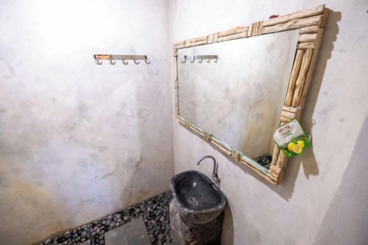 Un baño con lavamanos de piedra, un espejo con marco de madera y un perchero para toallas.