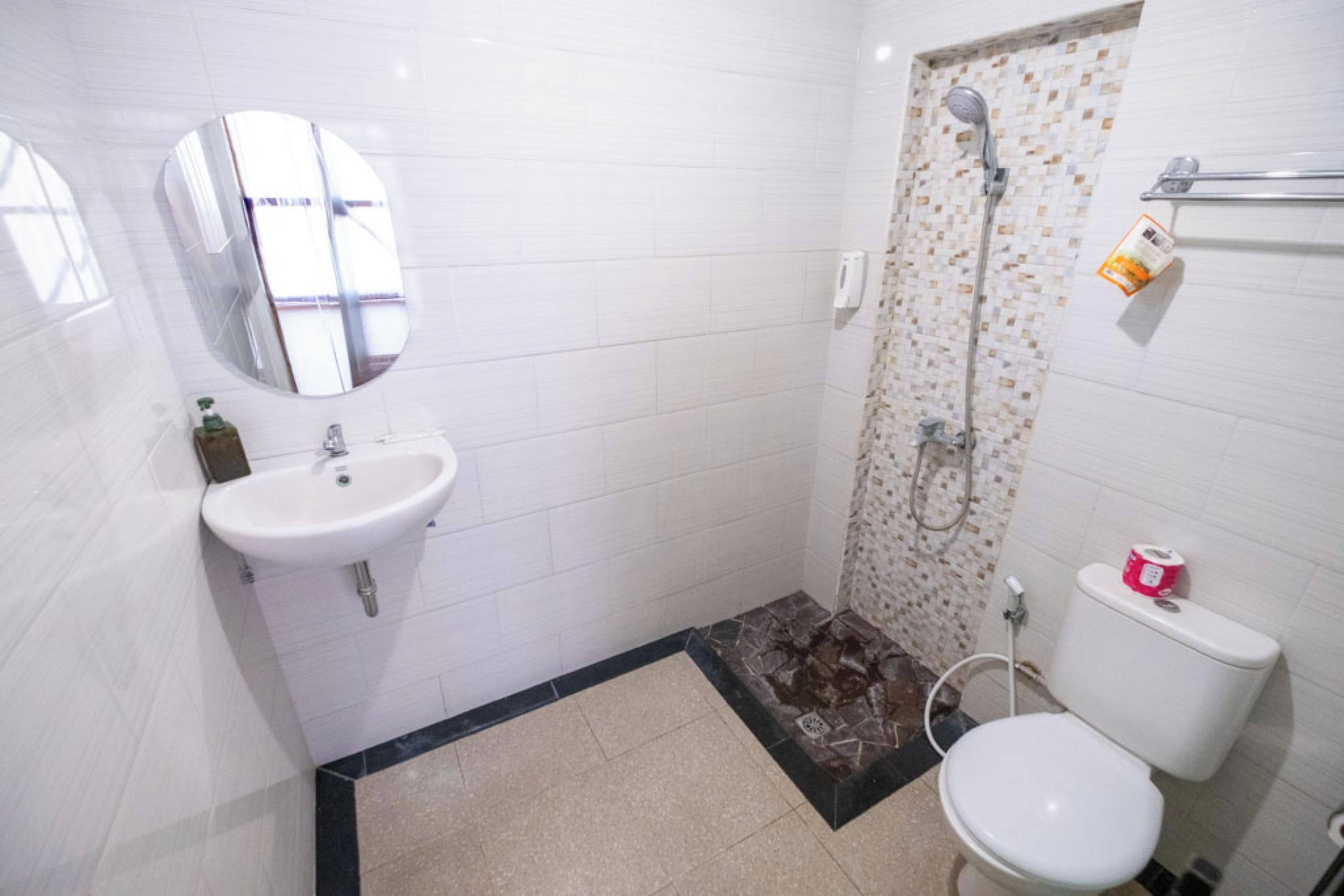 Un baño con lavamanos blanco, inodoro y ducha.