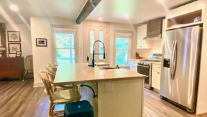 A modern kitchen with a central island, stainless steel appliances, and a dining area with chairs.