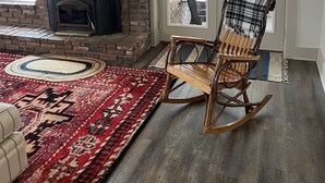 A cozy room with a brick fireplace, a rocking chair, and a patterned rug.