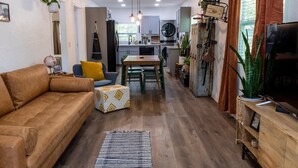 Un salon moderne avec un canapé, une table basse et un téléviseur. Il y a également un coin cuisine avec une table à manger et des chaises.
