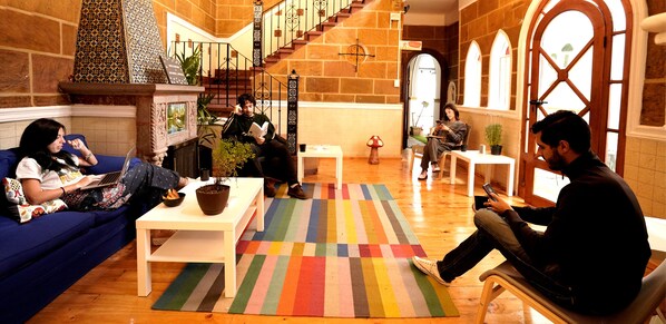 A spacious lobby with a staircase, a blue sofa, a white table, and a colorful striped rug. - Hostal Fungi Casa Rosa (Mexico City)