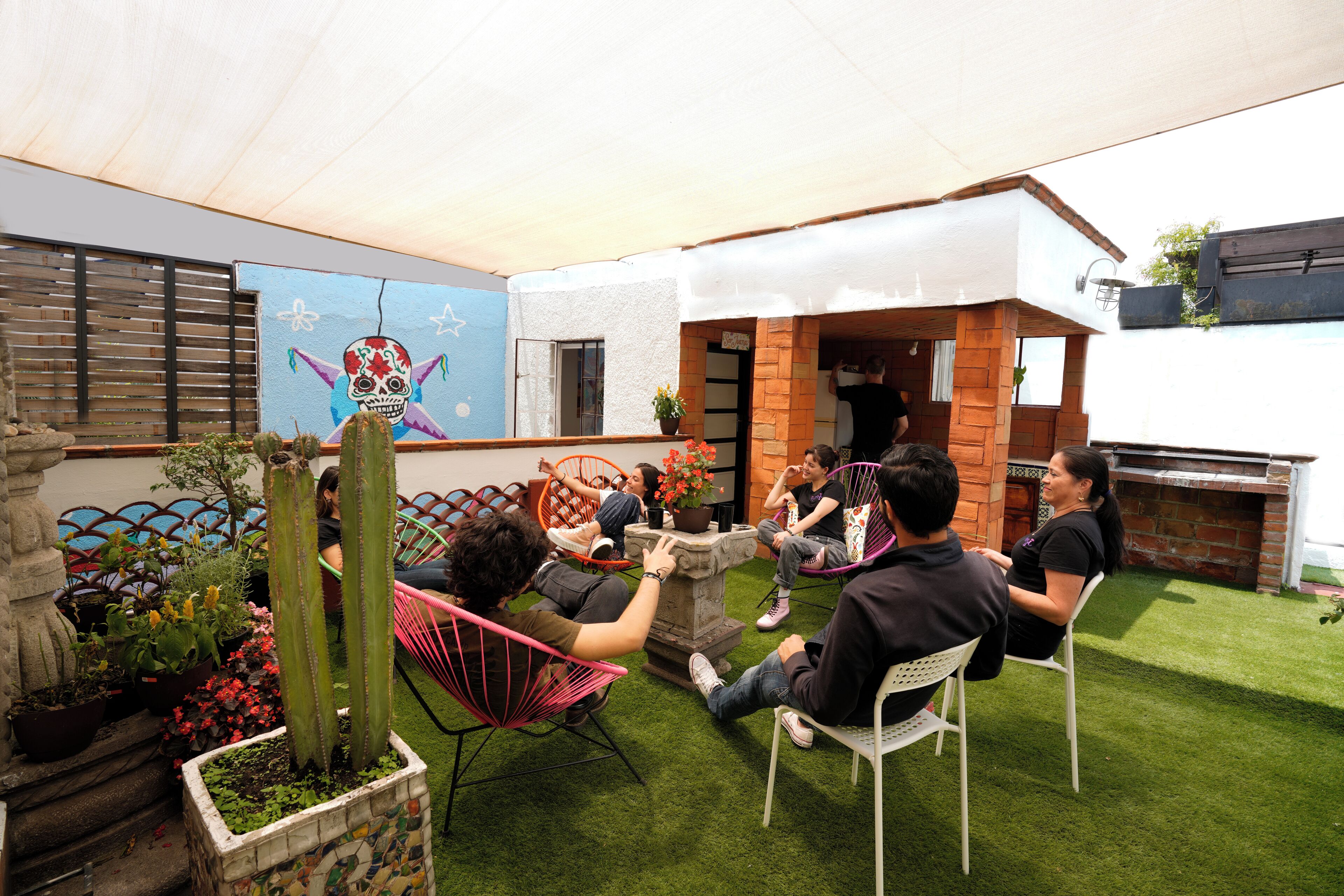 A patio area with a stone fountain, potted plants, and a mural on the wall.