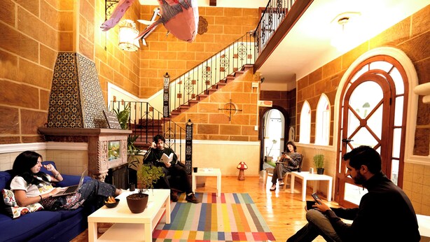 Un vestíbulo amplio con una escalera, una chimenea y un colorido tapete a rayas.