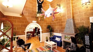 Un vestíbulo amplio con techo alto, una gran decoración de pez colgante, chimenea y una zona de estar con alfombra colorida.