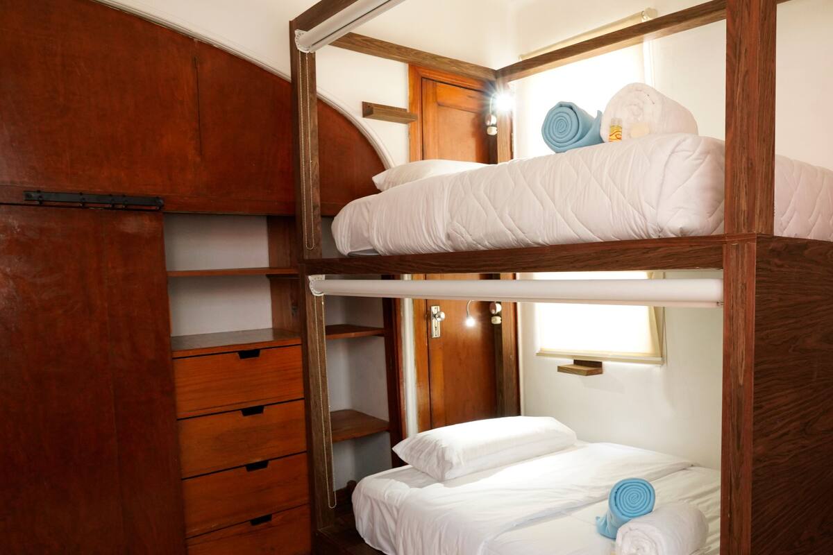A bunk bed room with wooden furniture, a wardrobe, and a small window.