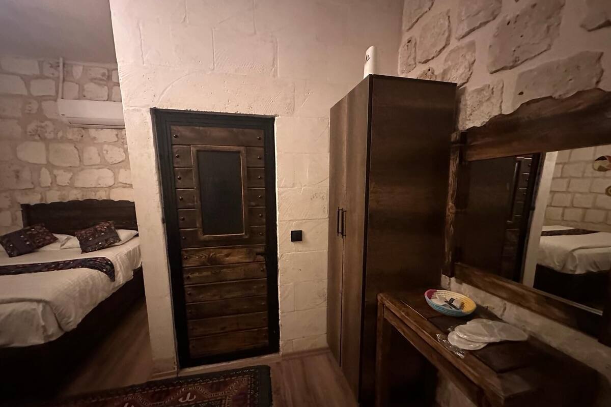 A room with a bed, a wardrobe, a mirror, and a small table with a bowl and a plate.